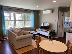Relax in this stylish living room with a sofa, flat-screen TV, and dining area.