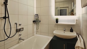 Ein modernes Badezimmer mit freistehender Badewanne, einem wandmontierten Waschbecken und einem großen Spiegel über dem Spiegelschrank.