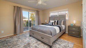 A bedroom with a bed, a nightstand, a ceiling fan, and a view of the outdoors. - Santa Fe Retreat Near Railyard and Artsy Delights (Santa Fe)