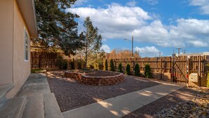 A backyard with a brick fire pit, gravel paths, and a wooden fence. - Santa Fe Retreat Near Railyard and Artsy Delights (Santa Fe)