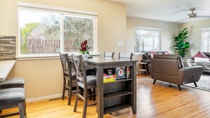 A spacious living room with a dining table, chairs, a sofa, and a large window. - Santa Fe Retreat Near Railyard and Artsy Delights (Santa Fe)