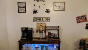 Kaffestation med kaffemaskine, kopper og et skilt, der siger "Coffee & Tea".