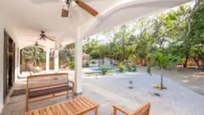 A covered outdoor area with wooden benches and a ceiling fan. - Cozy beach house, partial view, 2 mn walk to beach (Guanacaste Province)