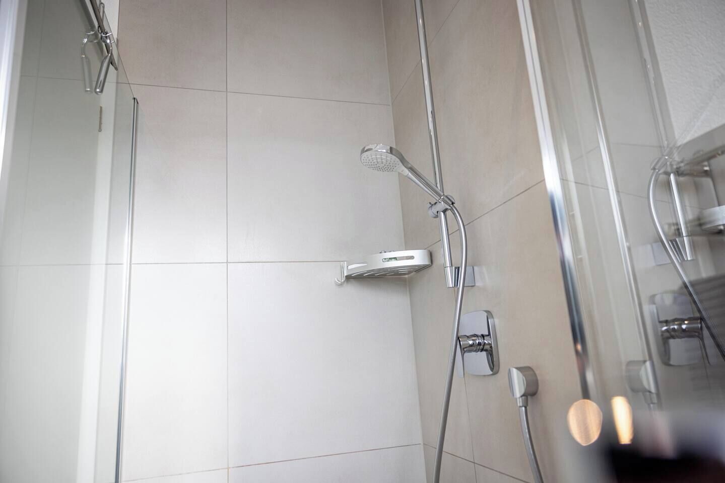 Eine moderne Dusche mit Handbrause und am Wand befestigtem Wasserhahn.
