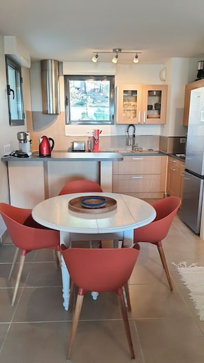 Una cocina moderna con una mesa de comedor redonda, sillas rojas y un horno empotrado.