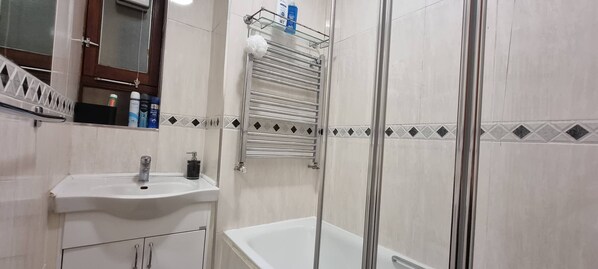 Baño con lavamanos, espejo y ducha.