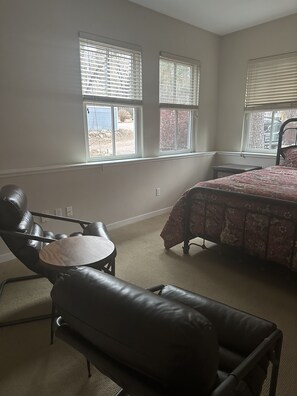 A bedroom with a bed, a chair, a small table, and two windows. - Nestled in Cheyenne Canyon and one minute walk to the Broadmoor hotel! (Colorado Springs)