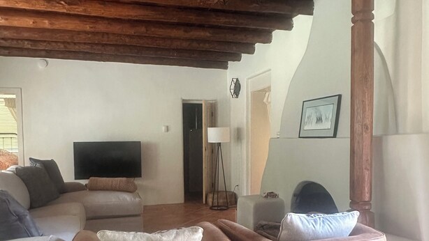 Een woonkamer met een houten plafond, een bank, een televisie en een open haard.