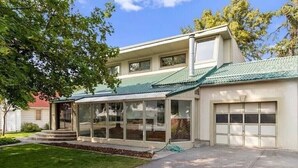 A two-story house with a green roof, a garage, and a covered porch area. - Cozy and Artistic Space with a library and a Floating Net (Idaho Falls)