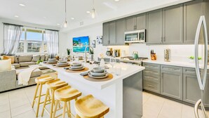 A modern kitchen with a central island, grey cabinets, and stainless steel appliances. - Lakeside Lottery/Game Room/EV (Indio)