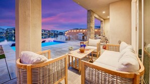 A balcony with wicker furniture, a pool, and a view of the city at dusk. - Lakeside Lottery/Game Room/EV (Indio)