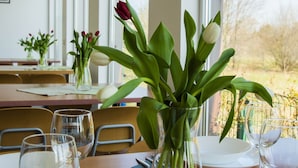 A dining table with a vase of flowers, empty wine glasses, and cutlery. - NaFali (Kosakowo)