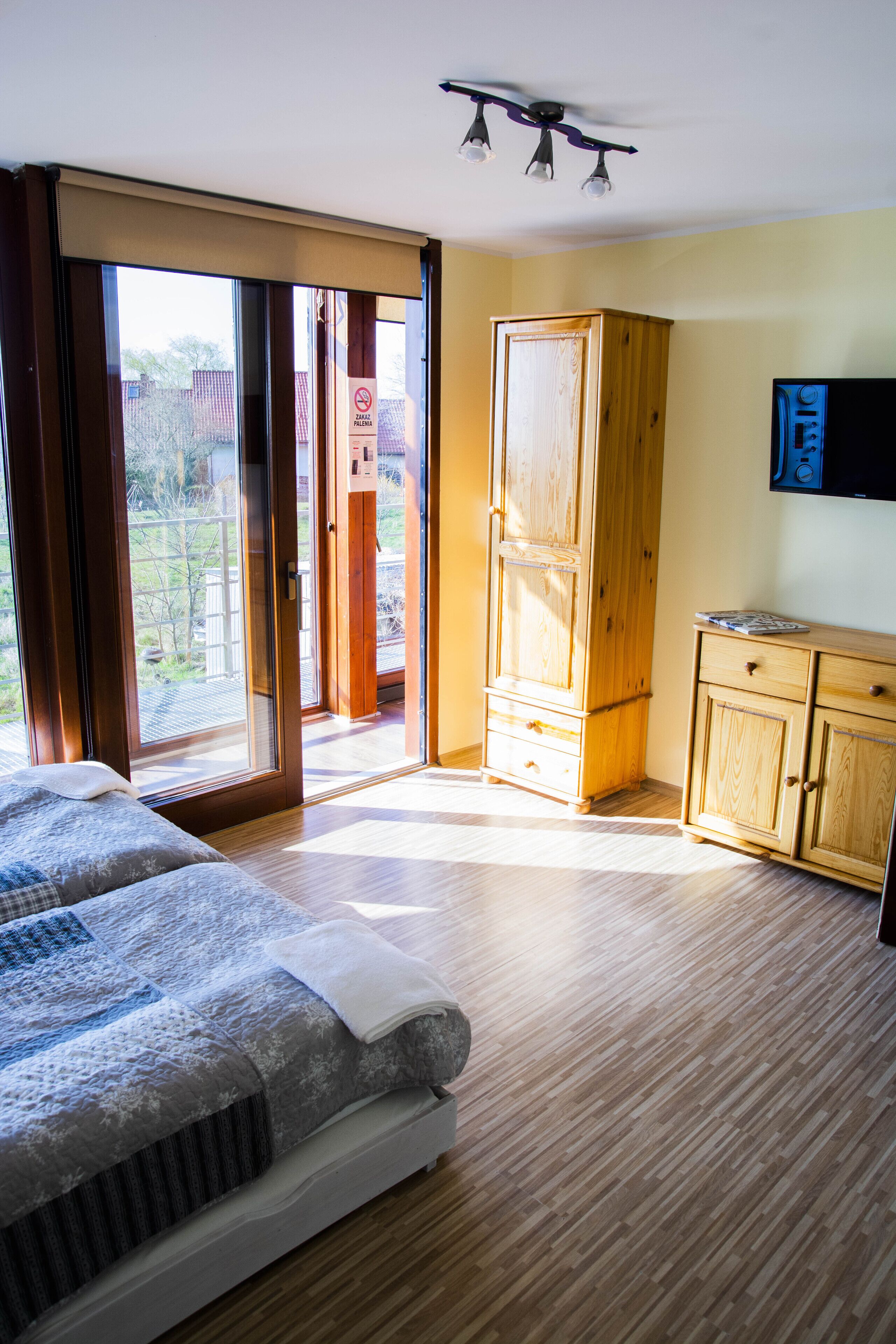 Ein Zimmer mit einem Bett, einem Holzschrank, einem Fernseher und einer Glastür zum Außenbereich.
