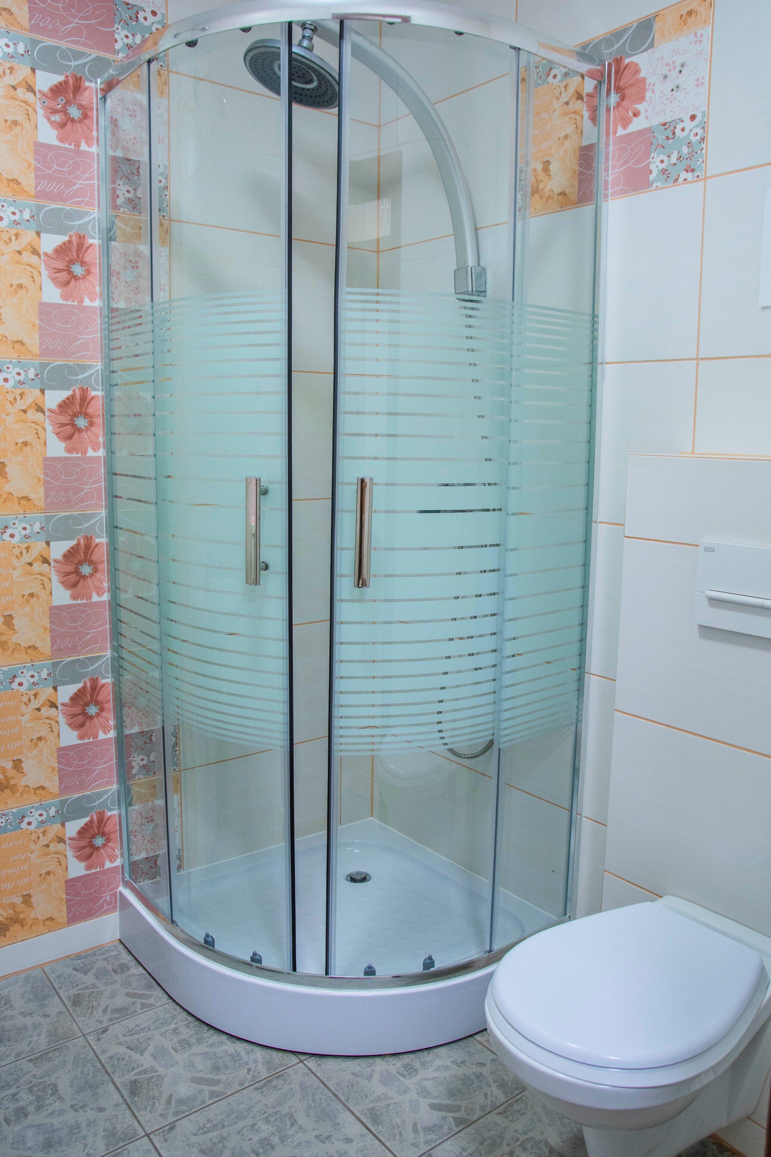 A glass-enclosed shower stall with a white toilet beside it.