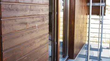 Fachada de madera con una escalera metálica que lleva a un porche cubierto.