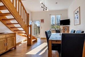 Enjoy meals in this stylish dining area with a large window, dining table, and mounted TV.