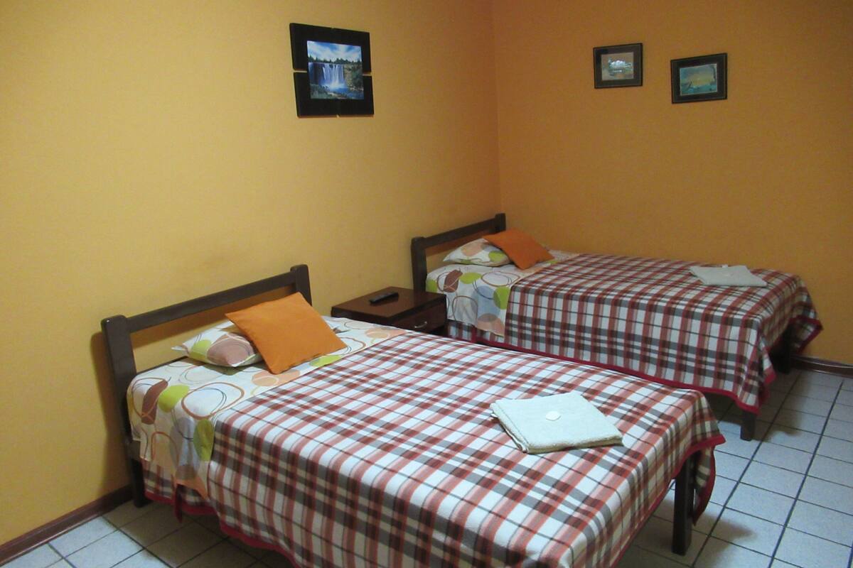Two single beds with checkered bedding, a nightstand, and a wall-mounted picture.