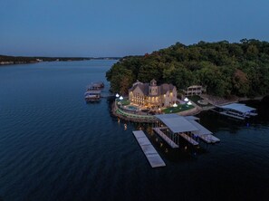 A lakeside property with a large house, dock, and boats. - The Lighthouse - 2026 VRBO OF THE YEAR - Private Heated Pool & Golf Course 7k SF (Osage Beach)