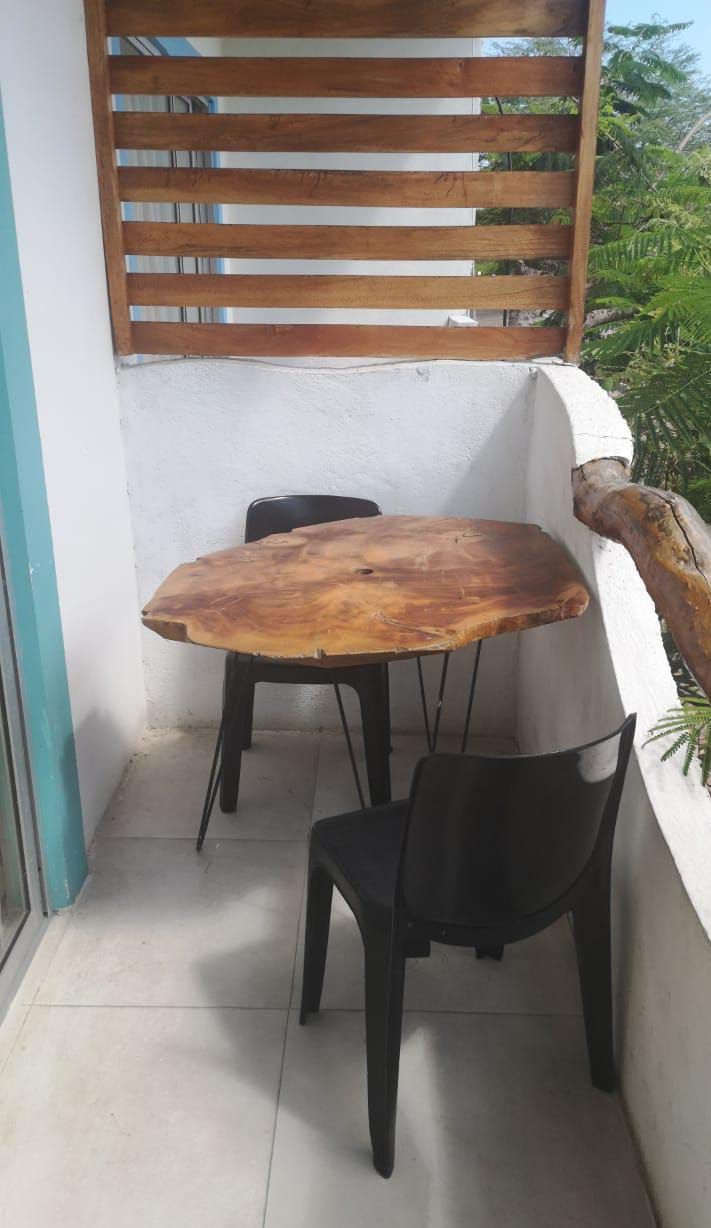 A small balcony with a wooden table and two chairs.