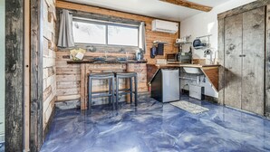 A compact kitchen with wooden walls, a window, a refrigerator, and a microwave. - Cozy Parowan Studio: 12 Mi to Brian Head Resort! (Parowan)