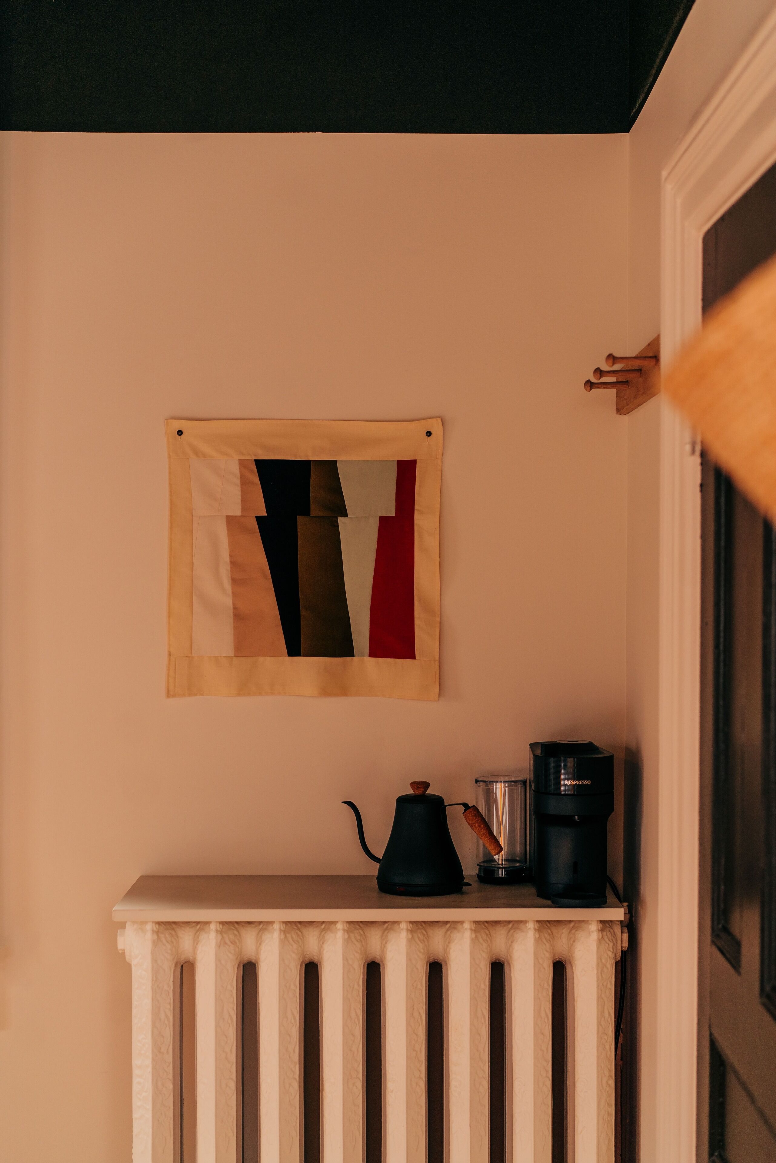 A room with a radiator, a coffee maker, and a kettle on a small table.