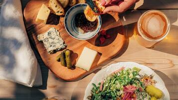 A wooden table with a variety of food items including cheese, bread, and a salad, along with glasses of wine.