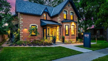 A two-story brick house with a gabled roof, a front porch, and a mailbox.