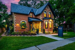 A two-story brick house with a gabled roof, a front porch, and a mailbox.