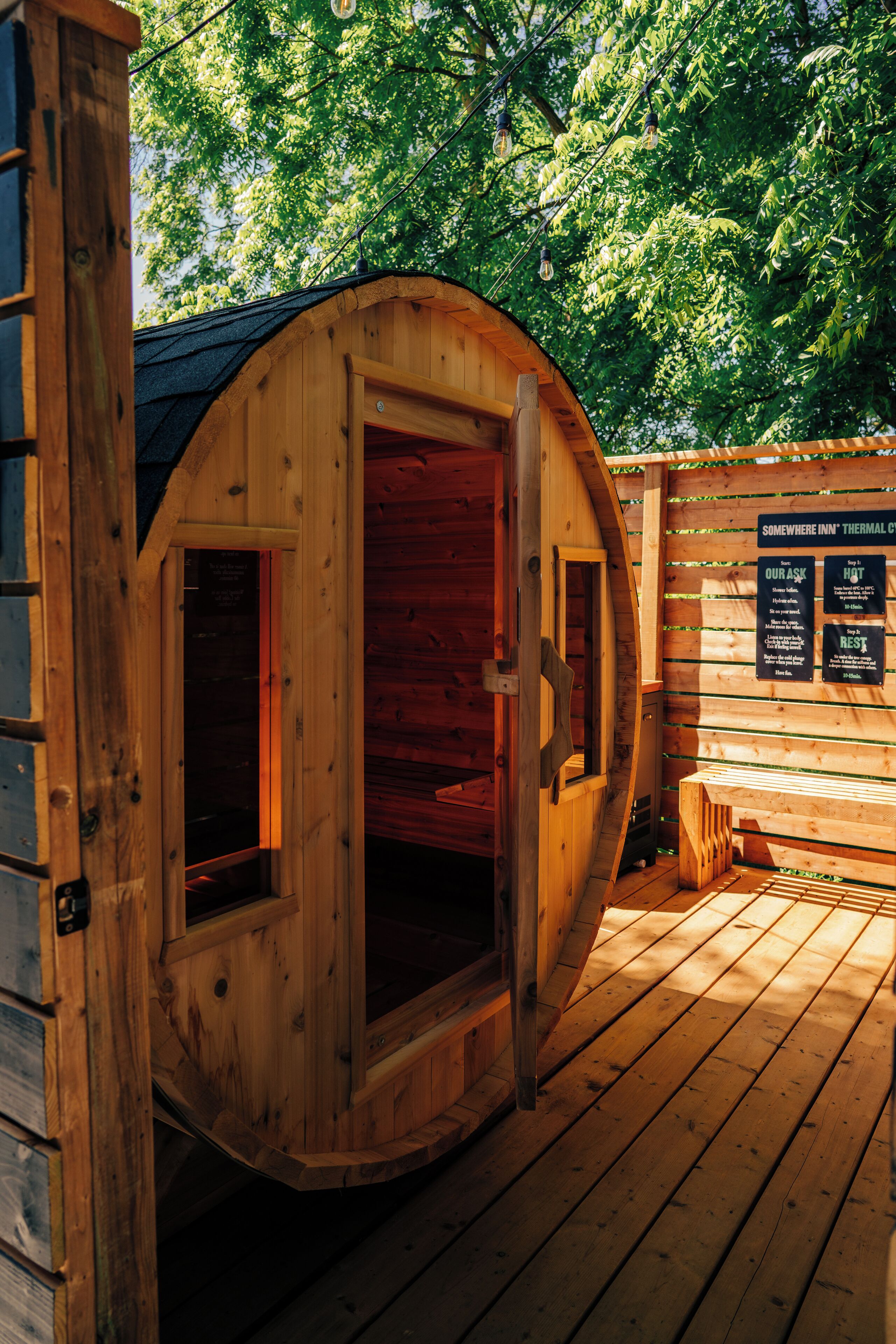 A wooden sauna with a curved roof, a wooden bench, and a wooden deck.