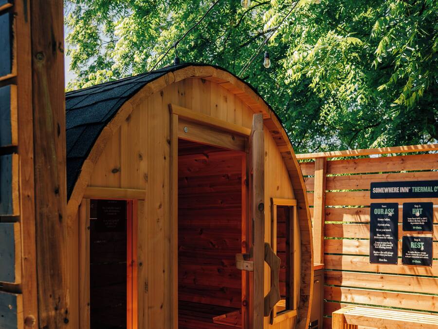 A wooden sauna with a curved roof, a wooden bench, and a wooden deck.