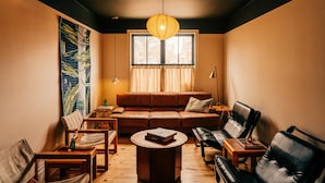 A cozy living room with a brown leather sofa, a wooden coffee table, and a hanging light fixture.