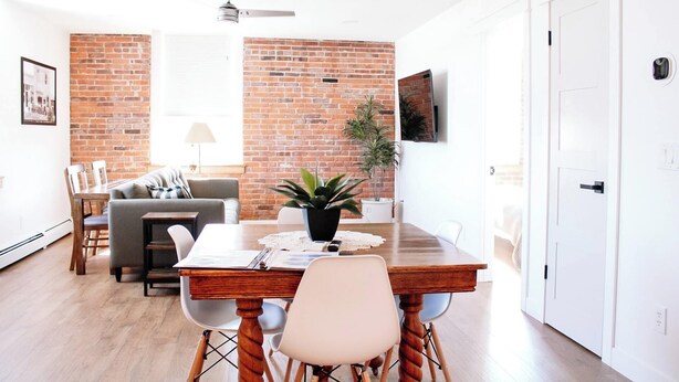 A dining area with a brick wall, a ceiling fan, and a potted plant. - 1890 Lofts - Harvester: Historic Loft • Near Amana Colonies, Winery, Outlet Mall (Williamsburg)