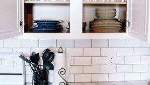 Une cuisine avec des meubles blancs, un plan de travail en marbre et une cuisinière.