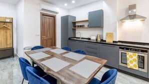 A modern kitchen with a wooden table, blue chairs, grey cabinets, and a stainless steel oven. - Luxury, one of a kind home, in Sliema ferries & AC (Tas-Sliema)