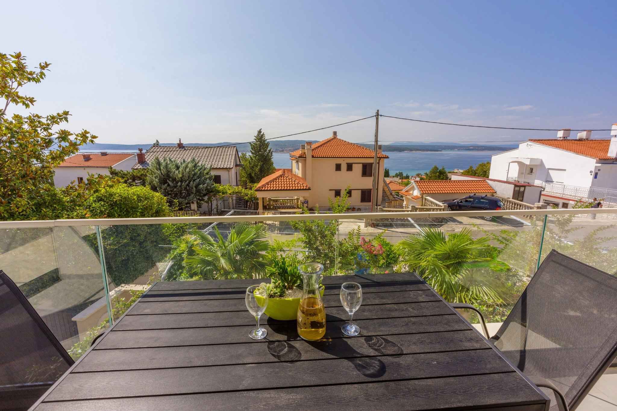 A balcony with a table, two wine glasses, and a bottle of wine.