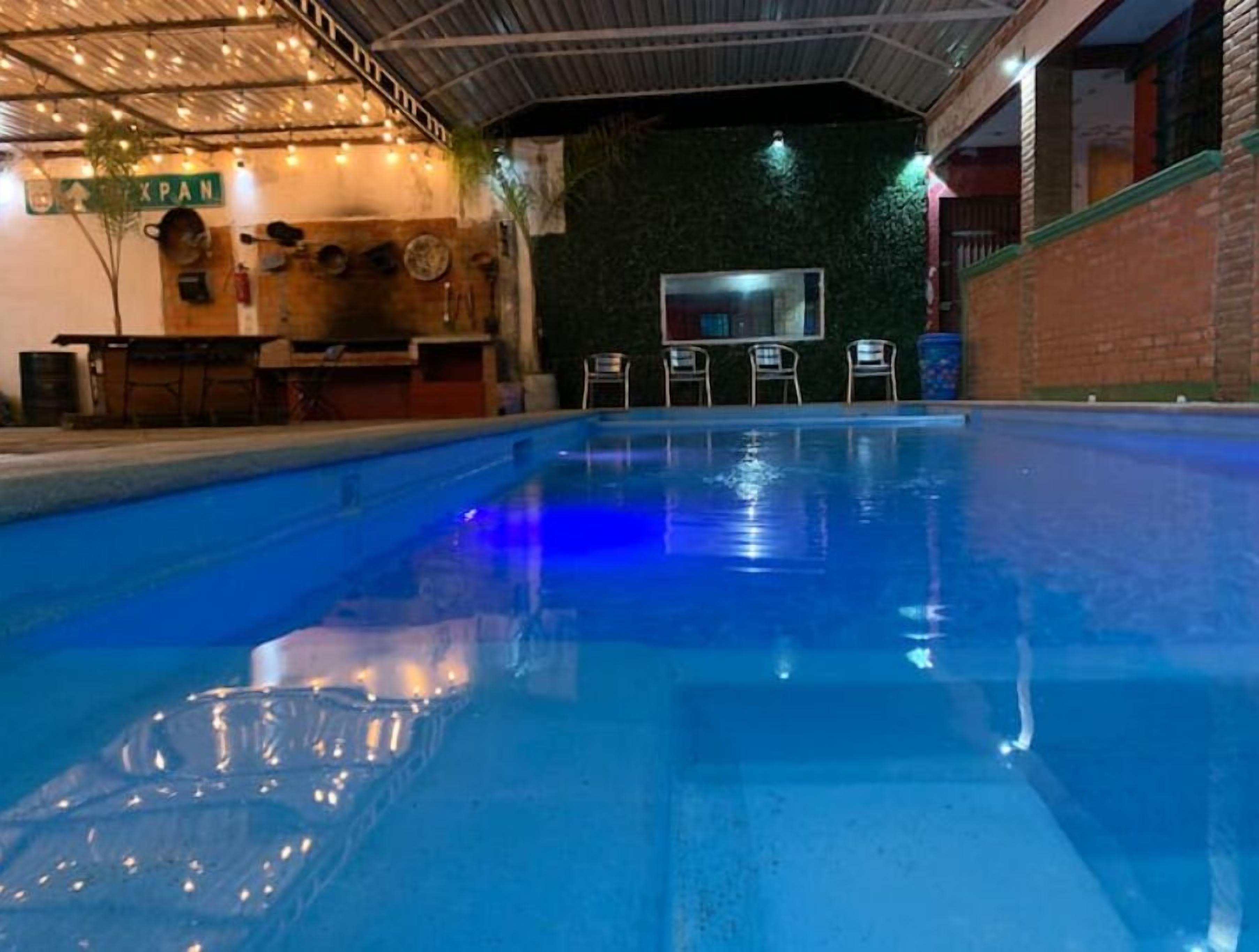 An indoor swimming pool with a clear view of the pool area, a reception desk, and a wall with a green sign.