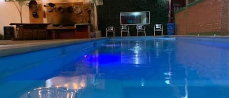 Une piscine intĂ©rieure offrant une vue dĂ©gagĂ©e sur lâensemble de lâespace piscine, un comptoir dâaccueil et un mur ornĂ© dâun panneau vert.