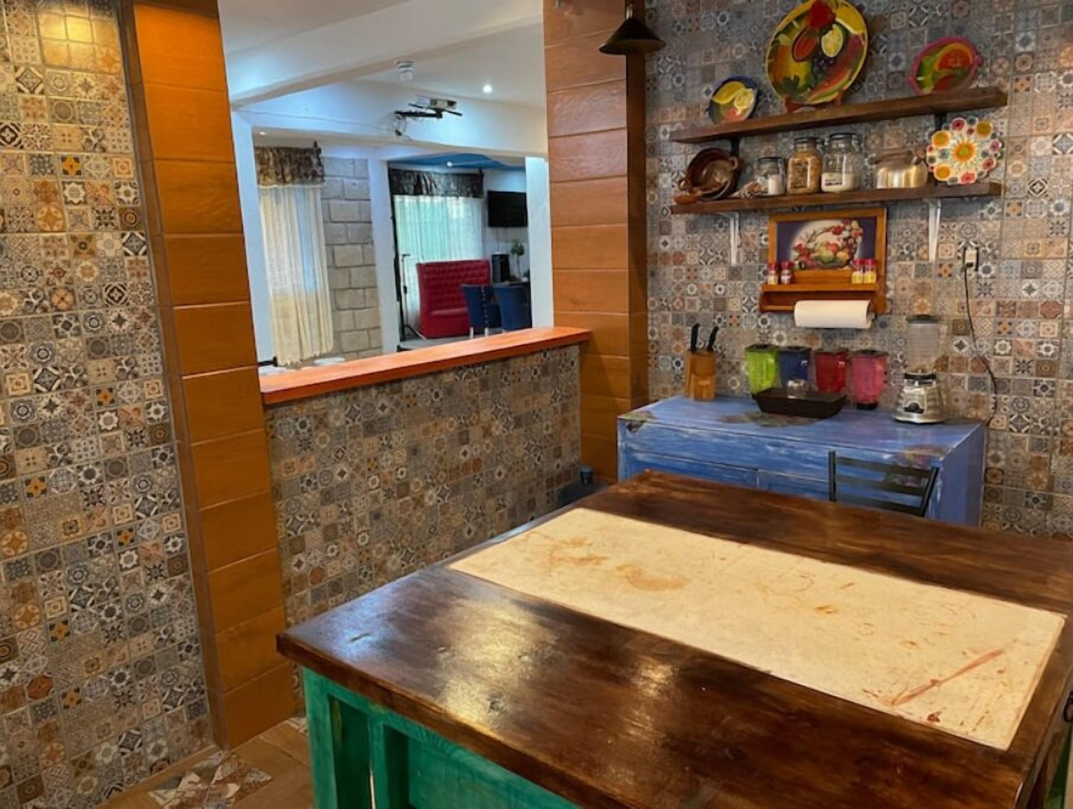 A kitchen with a wooden countertop, patterned tiles, and a blue cabinet.