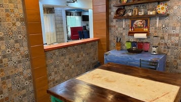 A kitchen with a wooden countertop, patterned tiles, and a blue cabinet.