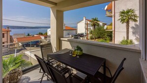 A balcony with a table and chairs, overlooking a residential area and a body of water.
