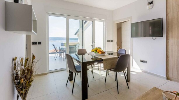 A modern dining area with a glass table, chairs, and a bowl of fruit. - Holiday apartment with shared-use pool (Crikvenica)