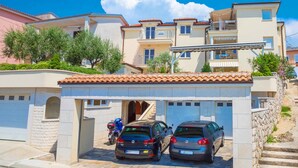 Un immeuble résidentiel doté d’un garage, de deux voitures garées et d’un escalier menant à l’entrée.