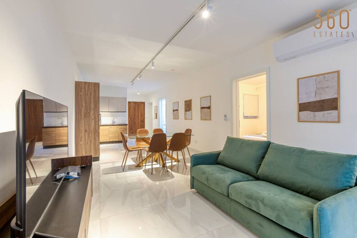 Een moderne woonkamer met een groene bank, een eethoek met een glazen tafel en stoelen, en een keuken op de achtergrond.