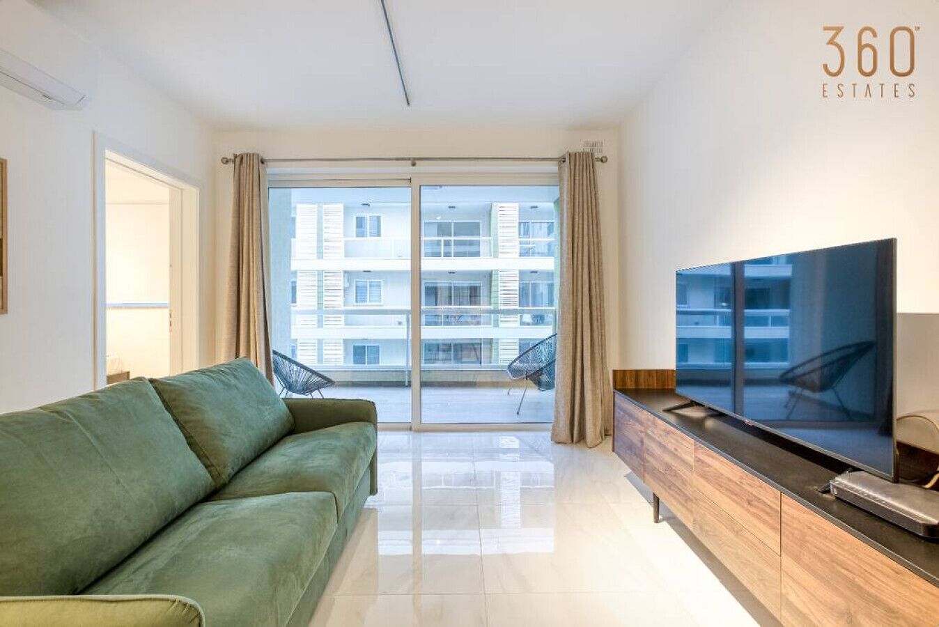 Een moderne woonkamer met een groene bank, een flatscreen televisie en een houten kast.