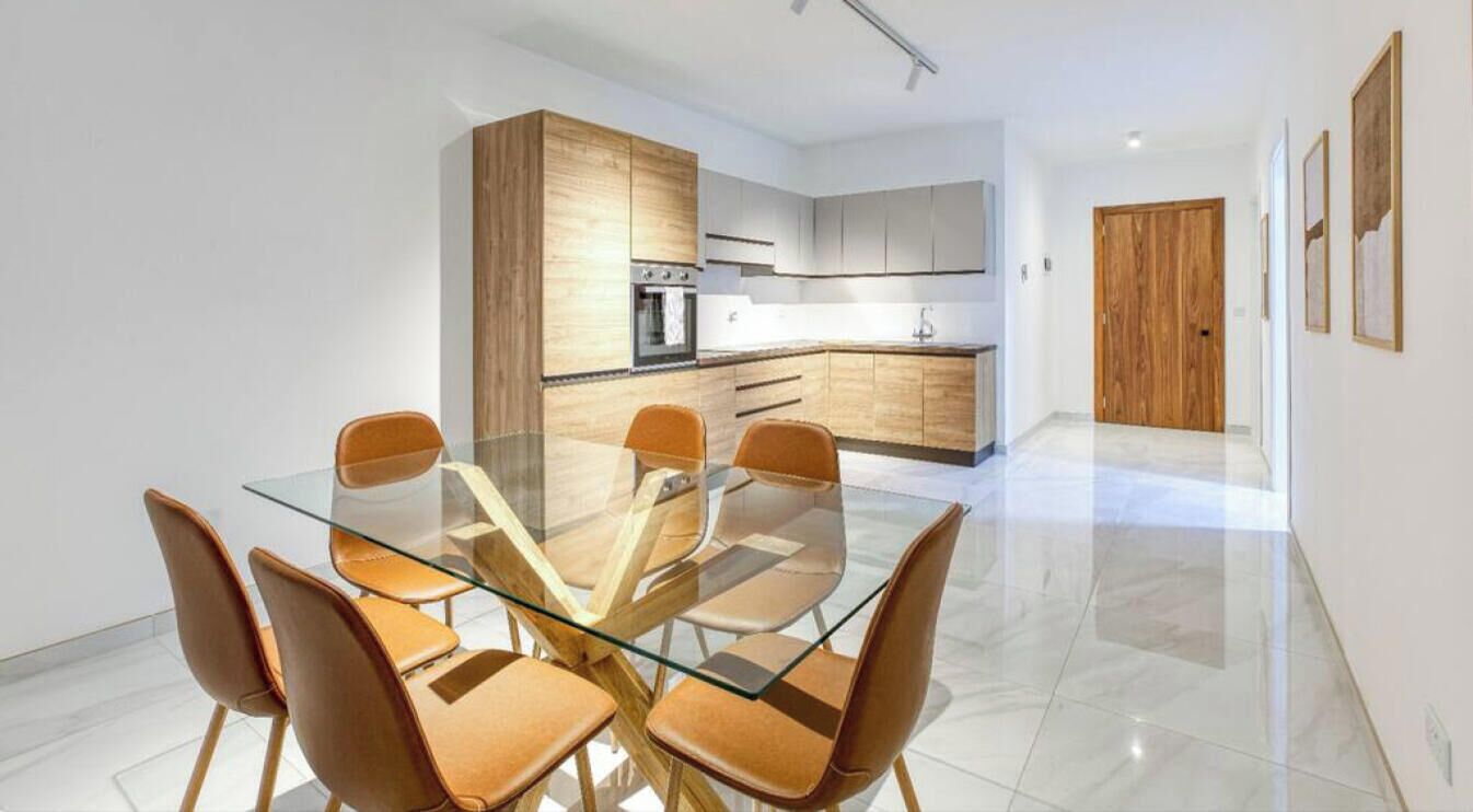 Une cuisine moderne avec des meubles en bois et une table à manger en verre, accompagnée de chaises.