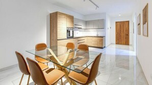 Eine moderne Küche mit Holzschränken und einem Glastisch mit Stühlen.