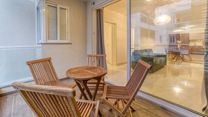 Ein Balkon mit Holzmöbeln und einer Glastür zum Wohnbereich.