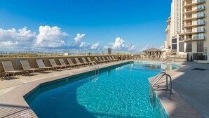 A swimming pool with lounge chairs and a high-rise building in the background. - Stunning Views from this 15th floor one bedroom condo! (Orange)