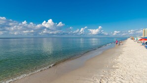 A beach with clear water, a sandy shore, and a few people walking. - Stunning Views from this 15th floor one bedroom condo! (Orange)