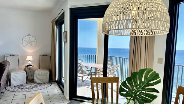 A balcony with a view of the sea, a dining area with a table and chairs, and a large decorative lamp. - Stunning Views from this 15th floor one bedroom condo! (Orange)